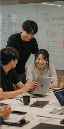 화이트보드 앞 테이블에 모여 함께 화면을 보는 팀원들